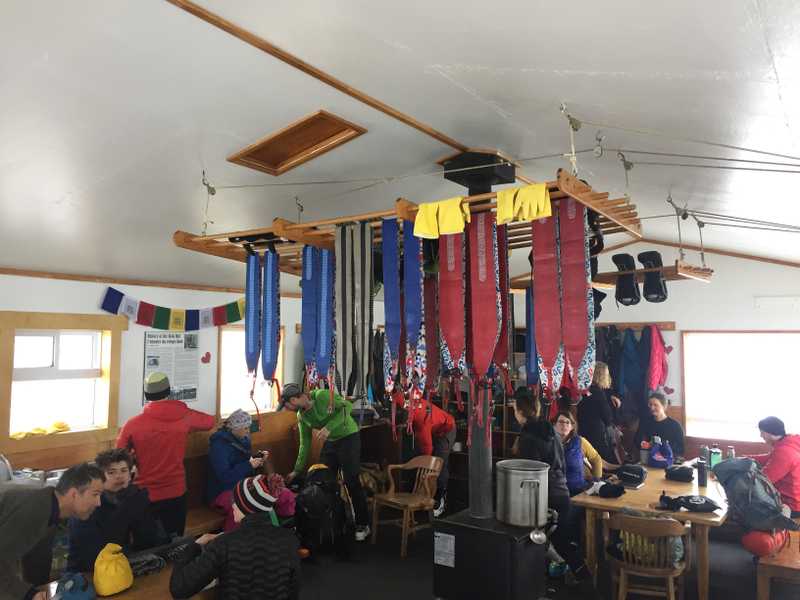 A large group of people in a hut drying out gear