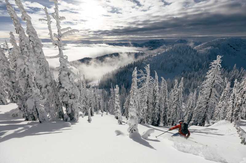 Skier in red jacket with foggy clouds in the background